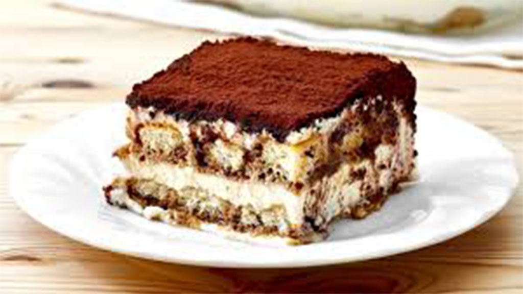 Pedaço de tiramisu servido em prato branco.