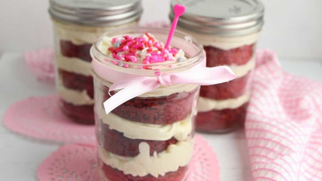 Torta de red velvet em pote com cobertura e granulados.