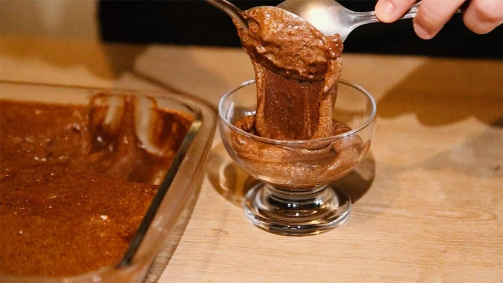 Pessoas servindo mousse de chocolate em taça